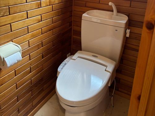 a white toilet in a bathroom with wooden walls at uliuli in Kuka