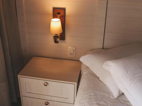 a bed with a night stand with a light on it at Paraíso do Salto in Lages