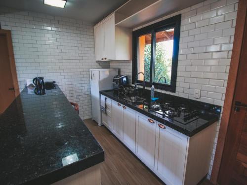 a kitchen with black counter tops and a white refrigerator at Paraíso do Salto in Lages