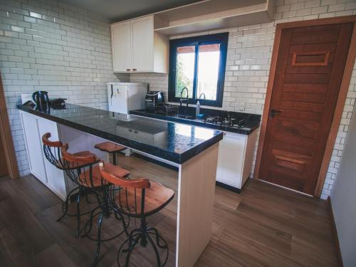 a kitchen with a counter with stools and a sink at Paraíso do Salto in Lages