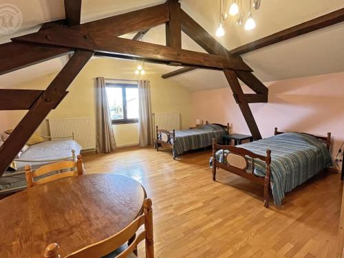 Una habitación con tres camas y una mesa dentro. en Gîte spacieux avec garage et terrasse dans un cadre verdoyant - FR-1-496-204, en Saint-Christo-en-Jarez