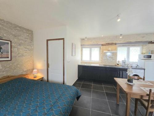 ein Schlafzimmer mit Bett und Tisch und eine Küche in der Unterkunft Studio cosy avec piscine partagée et étang privé, proche Bergerac et sites touristiques du Périgord - FR-1-616-207 in Naussannes