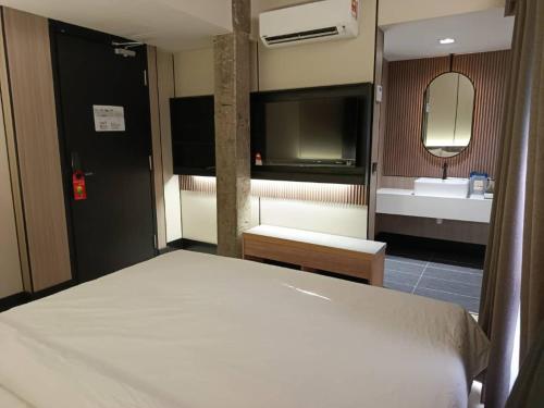 a bedroom with a bed and a bathroom with a sink at Urban Inn Cyberjaya in Cyberjaya