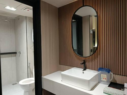 a bathroom with a sink and a mirror and a toilet at Urban Inn Cyberjaya in Cyberjaya