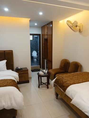 a hotel room with two beds and a chair at Osama's Room for Rent in Murree