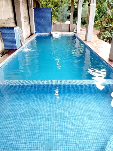 a pool with blue chairs and a swimming pool at Parijat-Breathtaking Sky and Hilltop view in Dapoli
