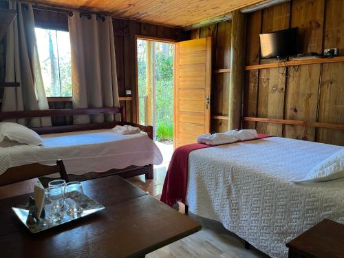 a bedroom with two beds and a table and a tv at Pousada São Miguel in Cunha