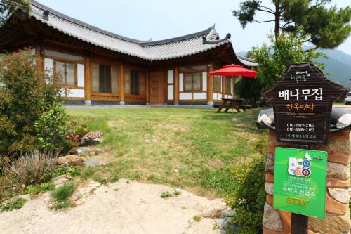 a sign in front of a chinese house with a building at Pear tree house Hanok in Suncheon