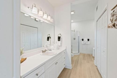 a white bathroom with a sink and a mirror at White Sand Beachfront Paradise in Gulf Shores