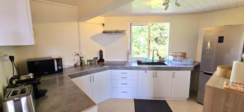 a kitchen with white cabinets and a sink and a window at LAKAZ DEL SOL - Modern and elegant apartments with luxurious garden, pool and barbecue area - Tourism Permit Certified in Tamarin