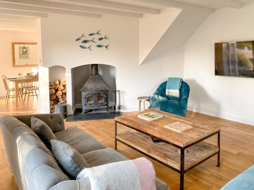 a living room with a couch and a table and a fireplace at Barn Cottage in Saint Mawgan