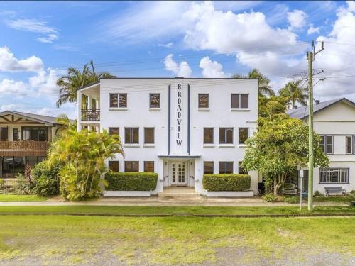 a large white building with trees in front of it at River View - Modern Living in a Vintage Apartment in Brunswick Heads