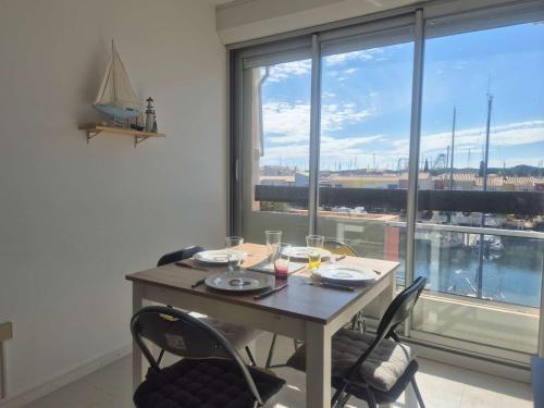 une table de salle à manger avec des chaises et une grande fenêtre dans l'établissement Studio cabine 4 personnes avec parking - Cap d'Agde - FR-1-249-424, au Cap d'Agde