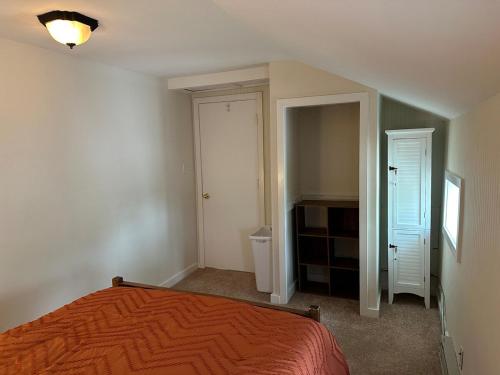 a bedroom with an orange bed and a closet at Comfy Classic Cute Apartment in Watertown