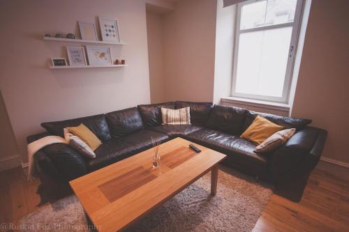 a living room with a black leather couch and a coffee table at Apartment B in Aberdeen