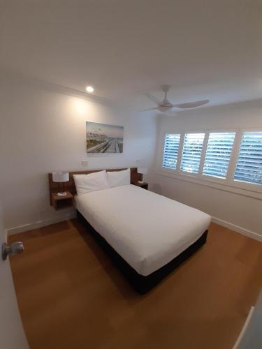 a bedroom with a white bed and two windows at Seashells Beachfront Resort in Diamond Beach
