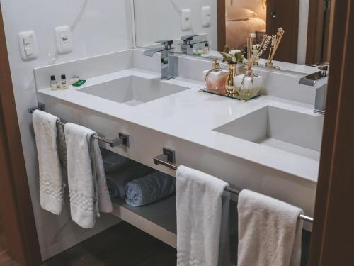 a white bathroom with a sink and towels at Paraíso do Salto in Lages