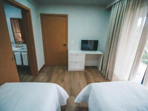 a bedroom with two beds and a television in it at Paraíso do Salto in Lages