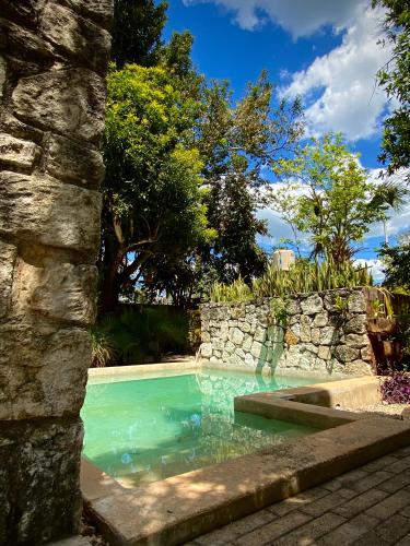 a swimming pool with a stone wall and blue water at Casona Uaymanaj in Uaymá