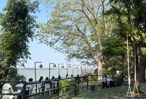 a group of people sitting on a fence near the water at Pilgrim's Kitchen & Inn in Savannakhet