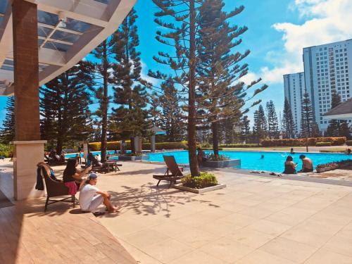 eine Gruppe von Personen, die in Liegen in der Nähe eines Swimmingpools sitzen in der Unterkunft Cloud Suite Tagaytay 2 in Kaybagal