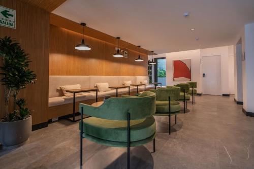 a waiting room with green chairs and a couch at Exclusive Mariano Santos 179 Residences by Geko in Lima