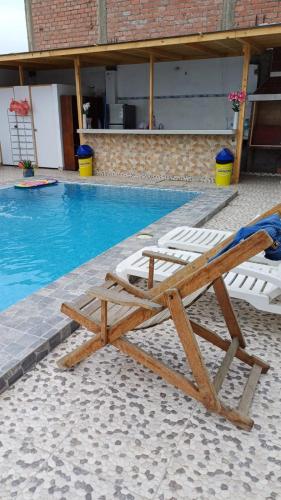 a wooden lounge chair next to a swimming pool at Hospedaje Los Lobos in Cerro Azul