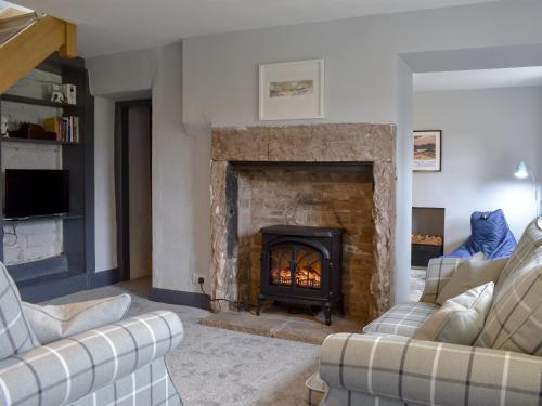 a living room with a fireplace and two couches at Toms Cottage in Melmerby