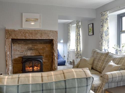 a living room with a fireplace and couches at Toms Cottage in Melmerby