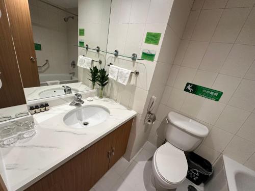 a bathroom with a sink and a toilet and a mirror at The North Garden Hotel Beijing Wangfujing-Located in the city center,adjacent to Wangfujing Street,Tiananmen Square,the Forbidden City, offering Beijing tour service in Beijing