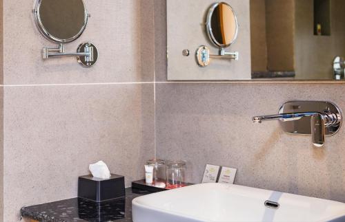 a bathroom with a toilet and a sink and mirrors at Hotel Anuttara Boudha, Kathmandu in Baudhatinchule