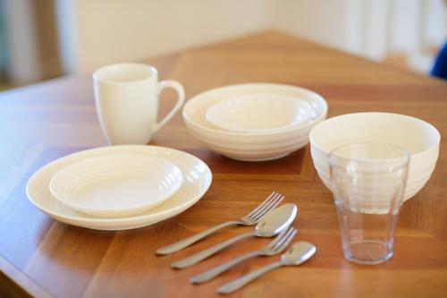 a wooden table with plates and utensils on it at Pool Villa Mito - Pool Villa 水戸 in Mito