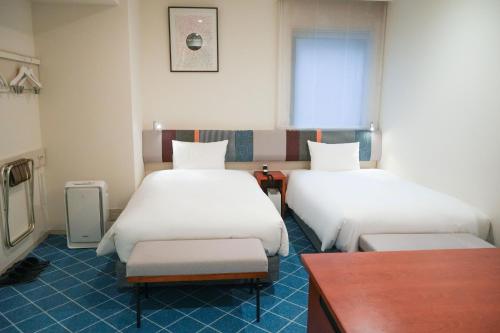 a hotel room with two beds and a table at Rembrandt Style Yokohama Sakuragicho in Yokohama