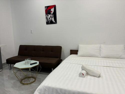 a bedroom with a white bed and a couch at Homestay Villa VINHOMES GRAND PARK QUẬN 9 in Gò Công