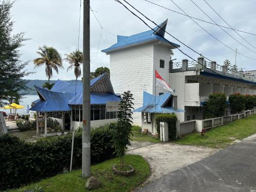 パラパトにあるSanggam Aek Sereの青い屋根とヤシの木がある白い建物