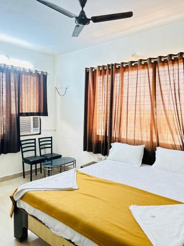 a bedroom with two beds and a table and windows at Hotel Mayur Residency in Kalyan