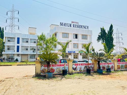 a white building with palm trees in front of it at Hotel Mayur Residency in Kalyan