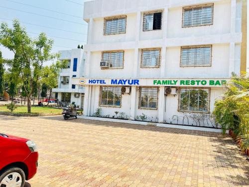 a building with a red car parked in front of it at Hotel Mayur Residency in Kalyan