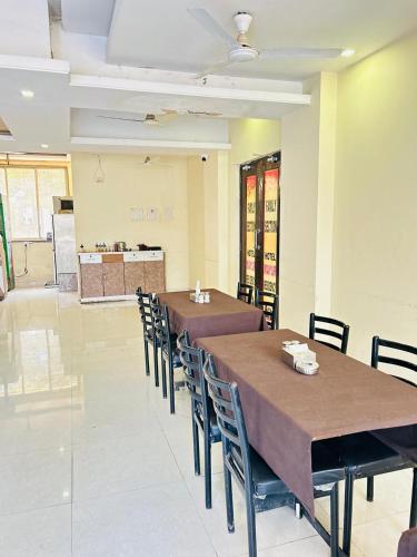 a dining room with two tables and chairs and a kitchen at Hotel Mayur Residency in Kalyan