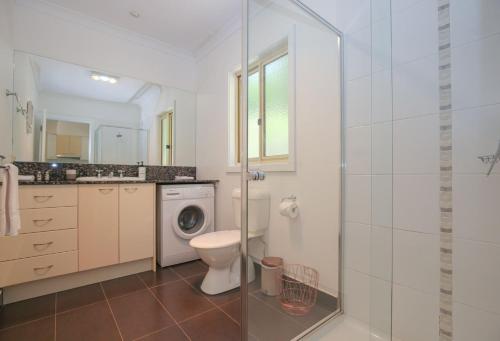 a bathroom with a toilet and a washing machine at Houghs Cabin in Bright