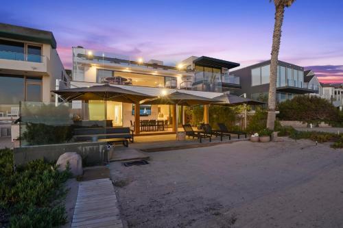 a large house with umbrellas and a patio at The Surf Lodge Villa in Malibu