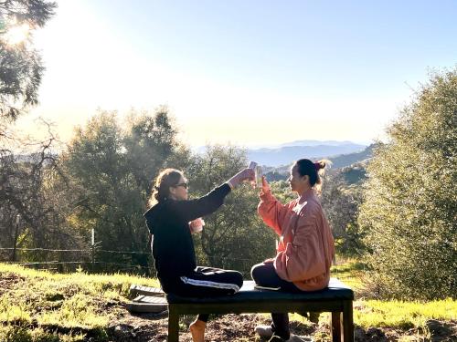 two women sitting on a bench giving each other a high five at Sequoia vacation home in Baker and Hall Airport