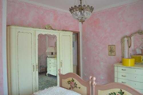 a bedroom with pink walls and a bed and a mirror at Le Bouganville Apartment in Desenzano del Garda