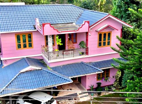 a pink house with a blue roof at Puzhayoram home stay, Palakkuli, Mananthavadi wayanad kerala in Mananthavady