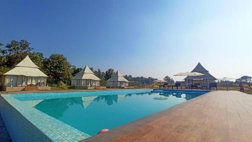 a large swimming pool with gazebos and a resort at Kingfisher Resort in Dhanwār