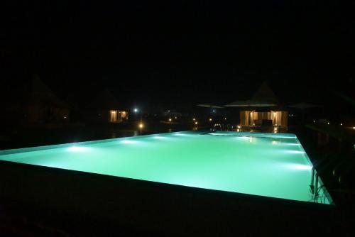 a large swimming pool lit up at night at Kingfisher Resort in Dhanwār