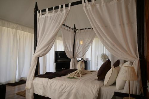a bedroom with a canopy bed with white curtains at Kingfisher Resort in Dhanwār