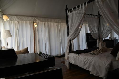 a bedroom with a bed with curtains and a couch at Kingfisher Resort in Dhanwār