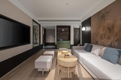 a living room with a white couch and a tv at JINGCADIA Hotel Nanjing Confucius Temple in Nanjing