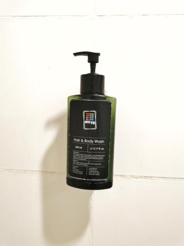 a black soap bottle sitting on a white wall at Hotel 98 in Kuching